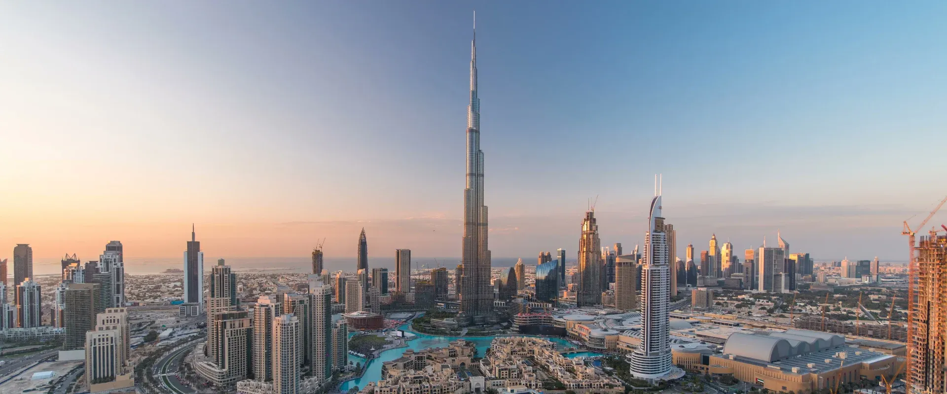 A panoramic view of Dubai's modern skyline at sunset, showcasing towering Burj Khalifa and Business Bay.